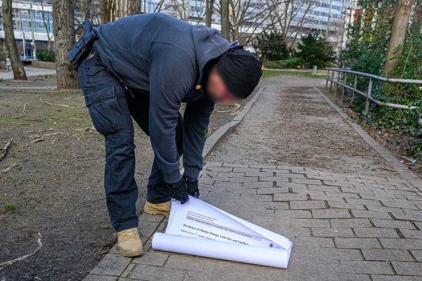 Zivilpolizist untersucht beschlagnamte Poster