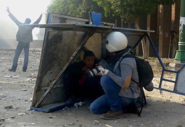 Journalist and boy take cover from stones thrown by rooftop militia