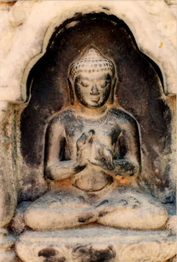 Buddha statue in niche with evidence of offerings, hands in teaching and intellectual discussion, or argument without fe