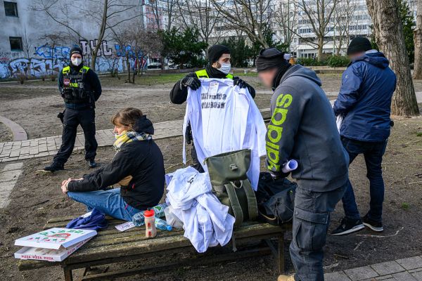 Polizisten durchsuchen Rucksäcke und Kittel mit der Aufschrift „Scientist Rebellion“