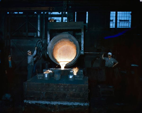 Two steel workers emptying out a large crucible of white-hot steel, Hamilton, Ontario / Deux sidérurgistes vident un gra