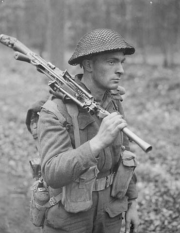 Pte H.E. Goddard of the Perth Regiment, carrying a Bren gun, in a forest north of Arnhem, Netherlands, April 1945 / Le s